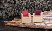 Zwei Sessel aus WPC auf Baumstämmen vor einem Holzpolter.